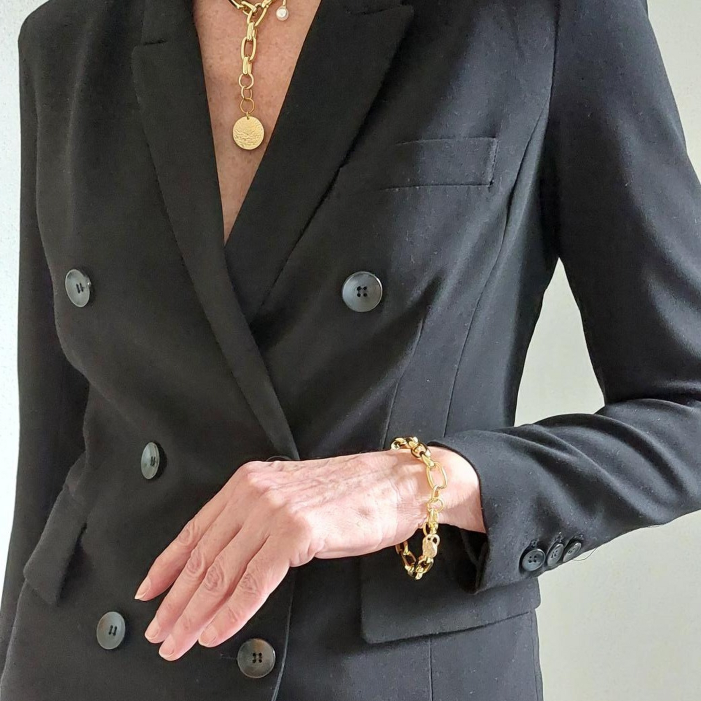 Exklusive breite goldfarbene Armkette aus Edelstahl. Die Kettenglieder sind breit und glänzend. Das Armband hat einen Karabinerverschluss, an einem Ende der Armkette ist ein 10mm gehämmertes rundes Plättchen aus vergoldetem Silber angebracht. Edelstahlschmuck von Hug the Lioness aus Österreich.