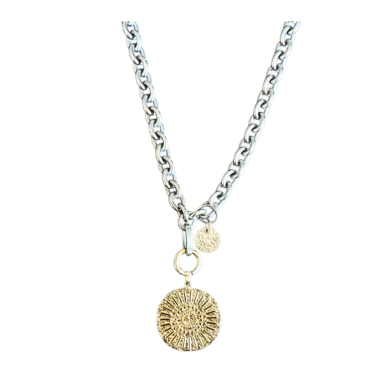 Breite Halskette aus silberfarbenem Edelstahl mit einem 23mm goldplattierten Münzanhänger. Der Anhänger hat ein abstraktes Hammerschlagmuster mit Strahlen. Handgefertigter Edelstahlschmuck der Schmuckmarke Hug the Lioness aus Österreich. Die Kette ist 6mm breit. Neben dem Karabiner ist ein 10mm vergoldetes, gehämmertes Plättchen aus Sterlingsilber angebracht.