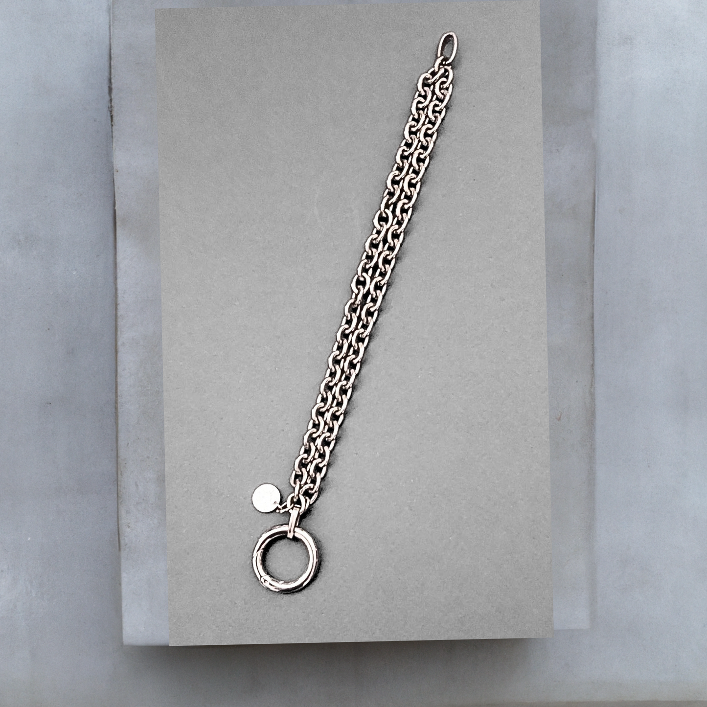 Doppelt verarbeitete Chunky Chain Armkette von Hug the Lioness aus dunklerem Edelstahl mit einem Ringverschluss. Neben dem Verschluss ist ein kleines Plättchen aus gehämmerten Sterlingsilber angebracht.