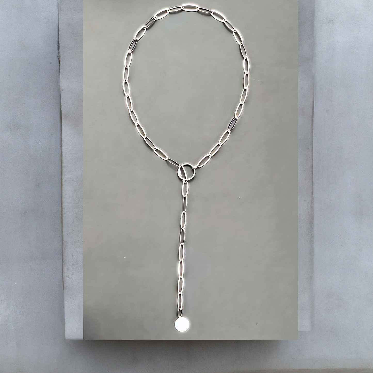 Lange Y-Lassokette aus hellem Edelstahl im Lariat Style. Das Kettenende mit dem gehämmerten Silberanhänger wird einfach durch den angebrachten Ring gezogen. Die Halskette ist 80cm lang und hat 7mm breite längliche Kettenglieder.