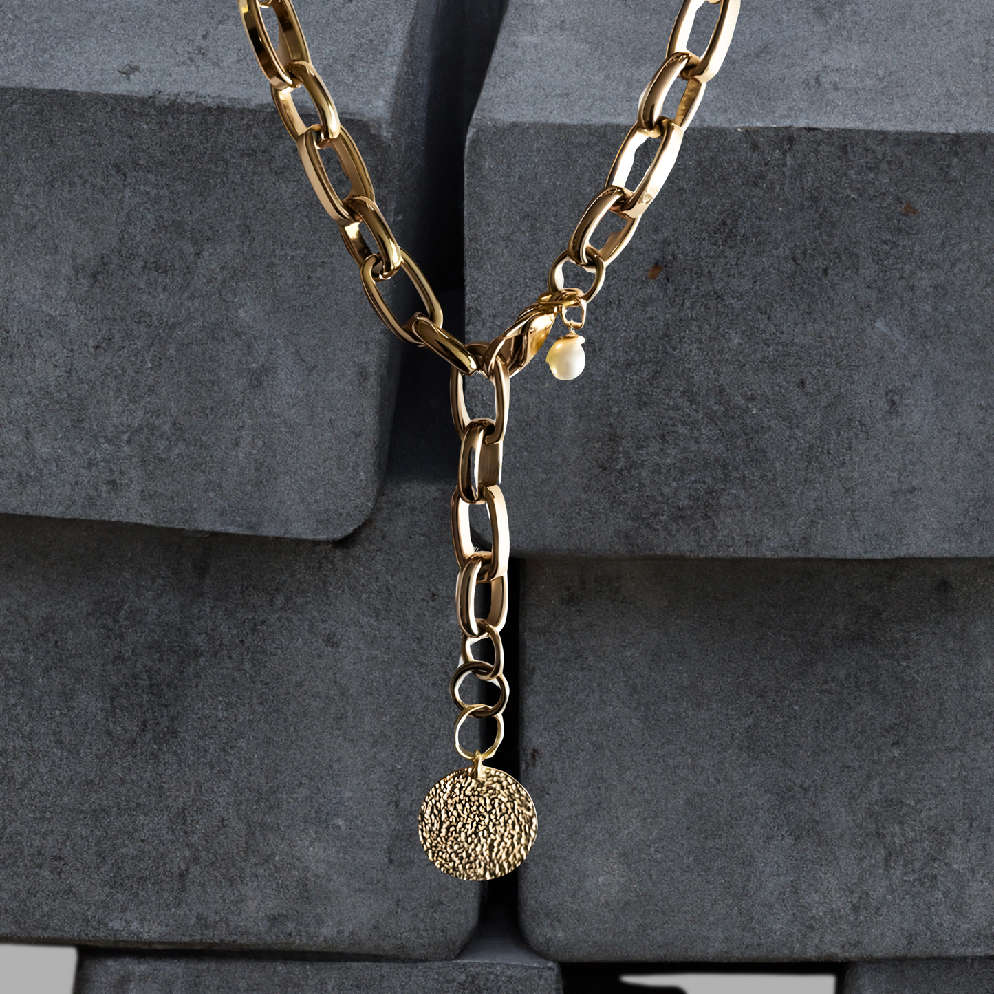 Exklusive goldfarbene Y-Halskette 47cm aus PVD beschichtetem Edelstahl. Die Kettenglieder sind breit und glänzend. Die Halskette hat einen vergoldeten 20mm Anhänger aus gehämmerten Sterlingsilber in Form einer Münze. Die 9mm breite Kette hat einen Karabinerverschluss der vorne flexibel zu schließen ist. Neben dem Karabiner ist eine 8mm Perle befestigt. Edelstahlschmucke von der Schmuckmarke Hug the Lioness aus Österreich.