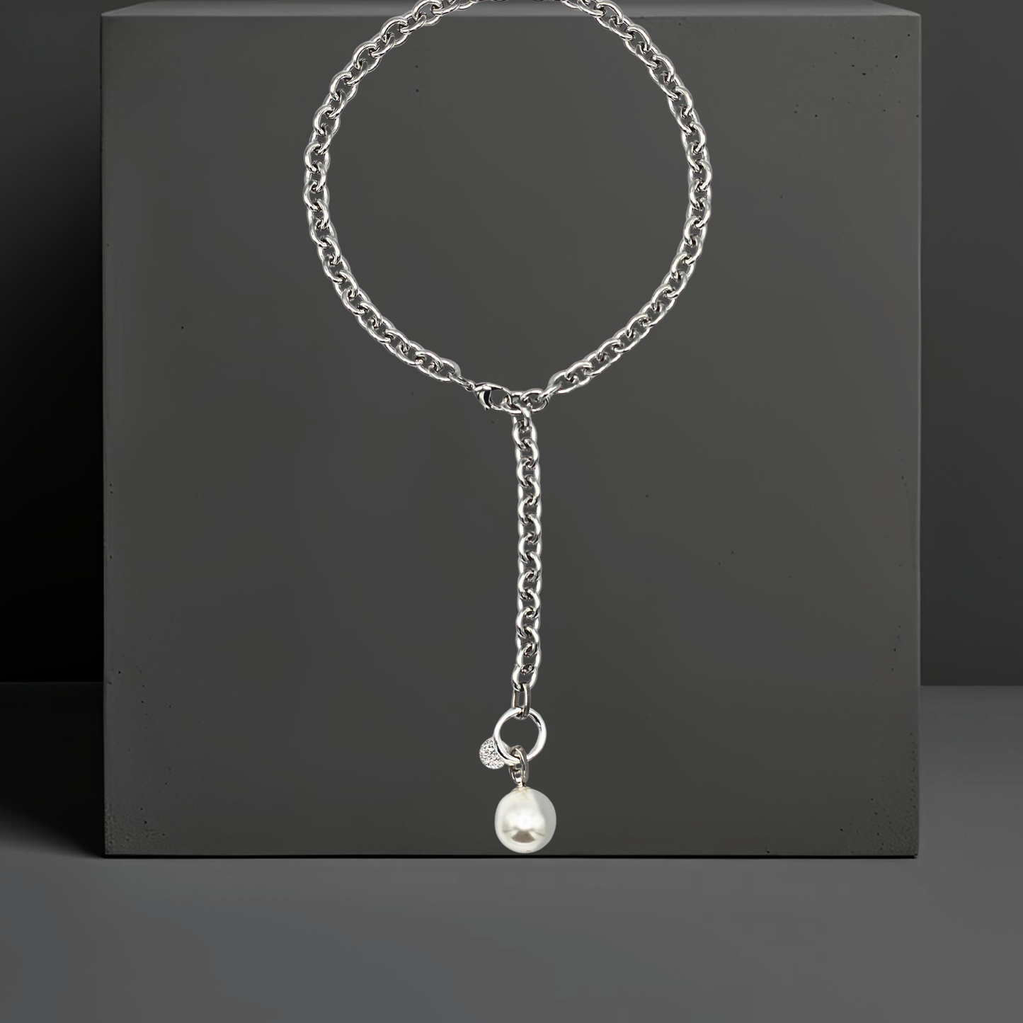 Moderne breite Y-Halskette Lariatkette aus silberfarbenem Edelstahl mit einer großen weissen Mallorcaperle, die an einem silberfarbenen Ring befestigt ist. Der Karabinerverschluss ist vorne flexibel zu schließen. Maximale Länge 50cm. An der Mallorcaperle ist auch ein kleines gehämmertes Plättchen aus Sterlingsilber befestigt. Die exklusive Halskette ist von der Schmuckmarke Hug the Lioness aus Wattens, Österreich und handgefertigt.