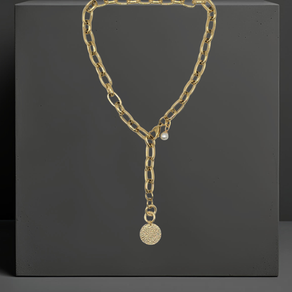 Exklusive goldfarbene Y-Halskette aus PVD beschichtetem Edelstahl. Mit einem Anhänger aus gehämmerten Sterlingsilber und einer Perle. Eleganter auffälliger Statementschmuck von der österreichischen Schmuckarke Hug the Lioness in Wattens, Tirol.