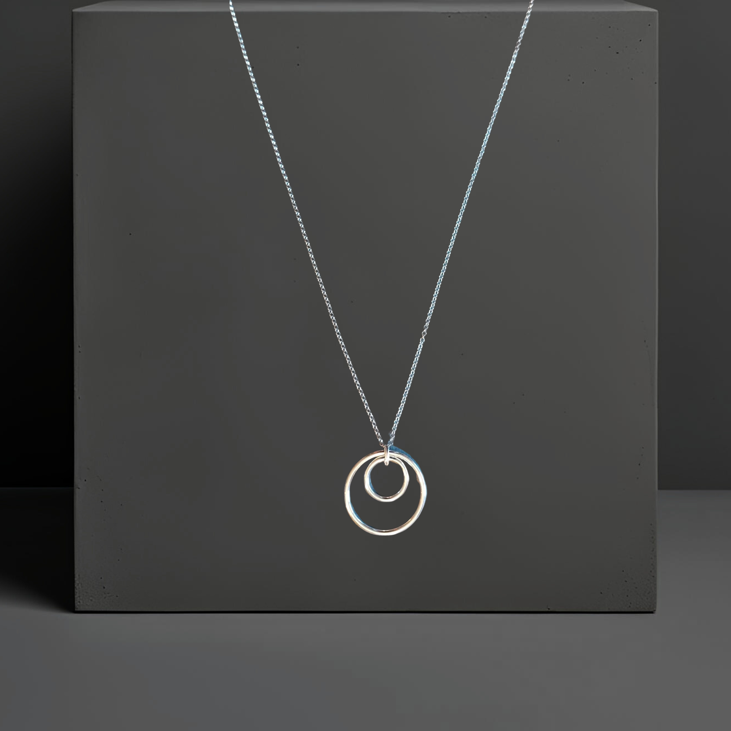 Feine 60cm Ankerkette in echt Silber. Der silberne Anhänger besteht aus zwei konzentrischen Ringen mit 16cm und 29cm. Die Kette hat einen Federringverschluss. Die Silberkette ist von der Schmuckmarke Hug the Lioness in Wattens, Österreich.