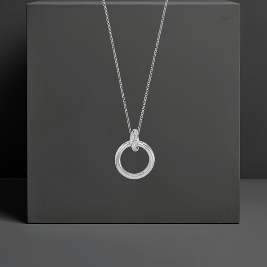 Sehr feine, kurze Ankerkette aus echt Silber 40cm mit einem Anhänger.  Ein Anhänger in Ringform ist mit einem weiteren verschlungenen kleinen Ring verbunden, durch den die Kette gezogen ist. Das Verlängerungskettchen ist 5cm. Von Hug the Lioness aus Wattens, Österreich.