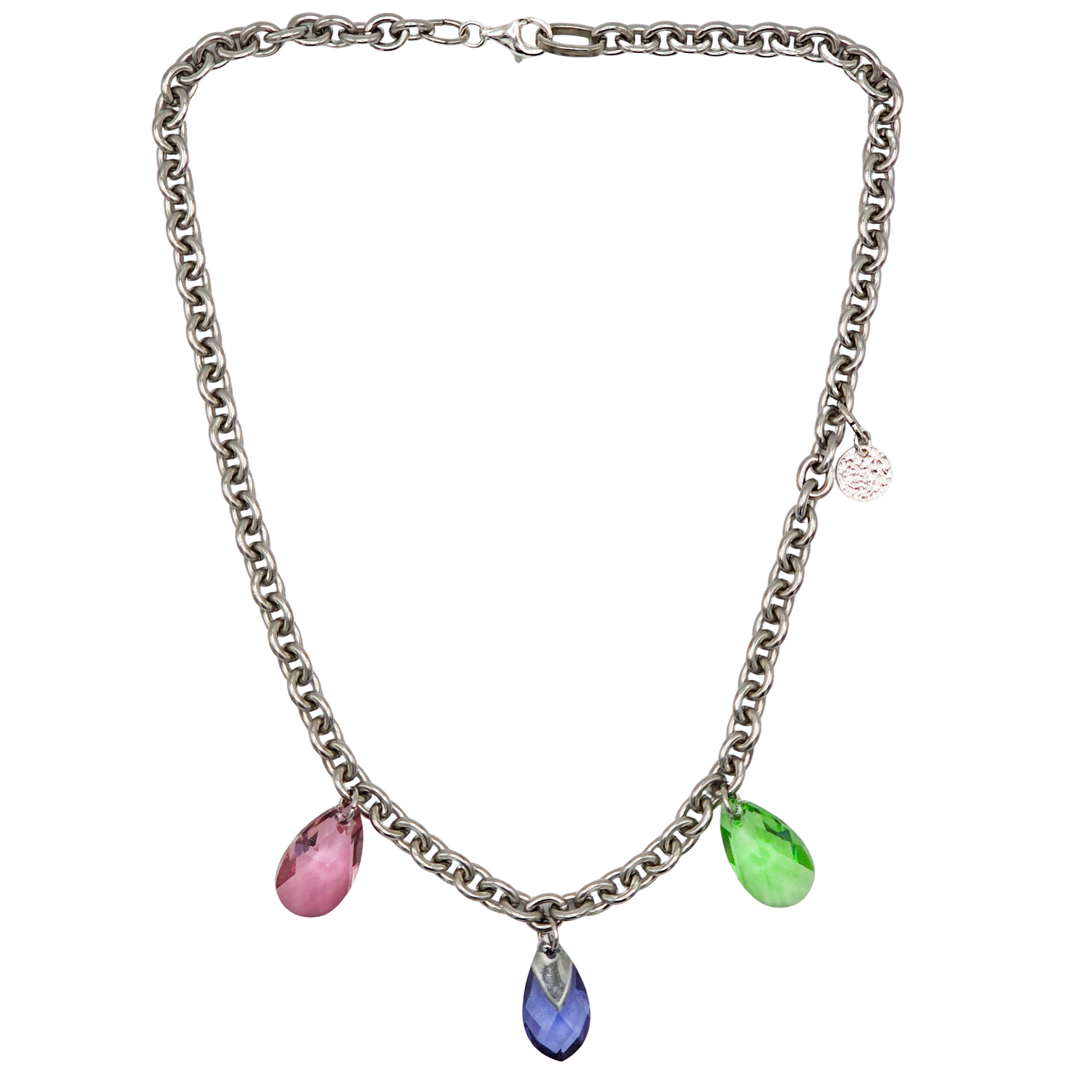 Collier aus Edelstahl, silberfarbene Gliederkette vorne mit 3 Kristalltropfen in rose, violett und grün. Die Kette ist 43cm lang und hat einen Karabinerverschluss. An der Seite ist in kleines gehämmertes Plättchen aus 925 Sterlingsilber angebracht. Die Kette ist aus der Kollektion JOY der Schmuckmarke HUG THE LIONESS.