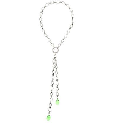 Handgefertigte breite Gliederkette aus rostfreiem Edelstahl mit einem Ringverschluss vorne. Im Ringverschluss ist ein langer Anhänger angebracht, der aus 2 Ketten (17cm und 25cm) und jeweils einem peridot grünem Kristalltropfen am Ende der Ketten besteht. Der lange Anhänger kann auch abgenommen werden und die Kette mit dem Ringverschluss als kurzes Collier getragen werden. Die Halskette ist von der Schmuckmarke Hug the Lioness aus Österreich.