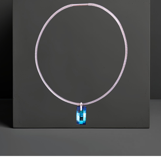 Elegante silberfarbene Mesh Halskette aus Edelstahl für Damen mit einem großen rechteckigen blauen Kristallanhänger in der Farbe Bermuda Blue. Das moderne Collier ist 45cm lang und stabil wie ein Halsreif. Der Kristall wurde in Österreich hergestellt. Das Collier ist von Hug the Lioness in Wattens, Österreich.