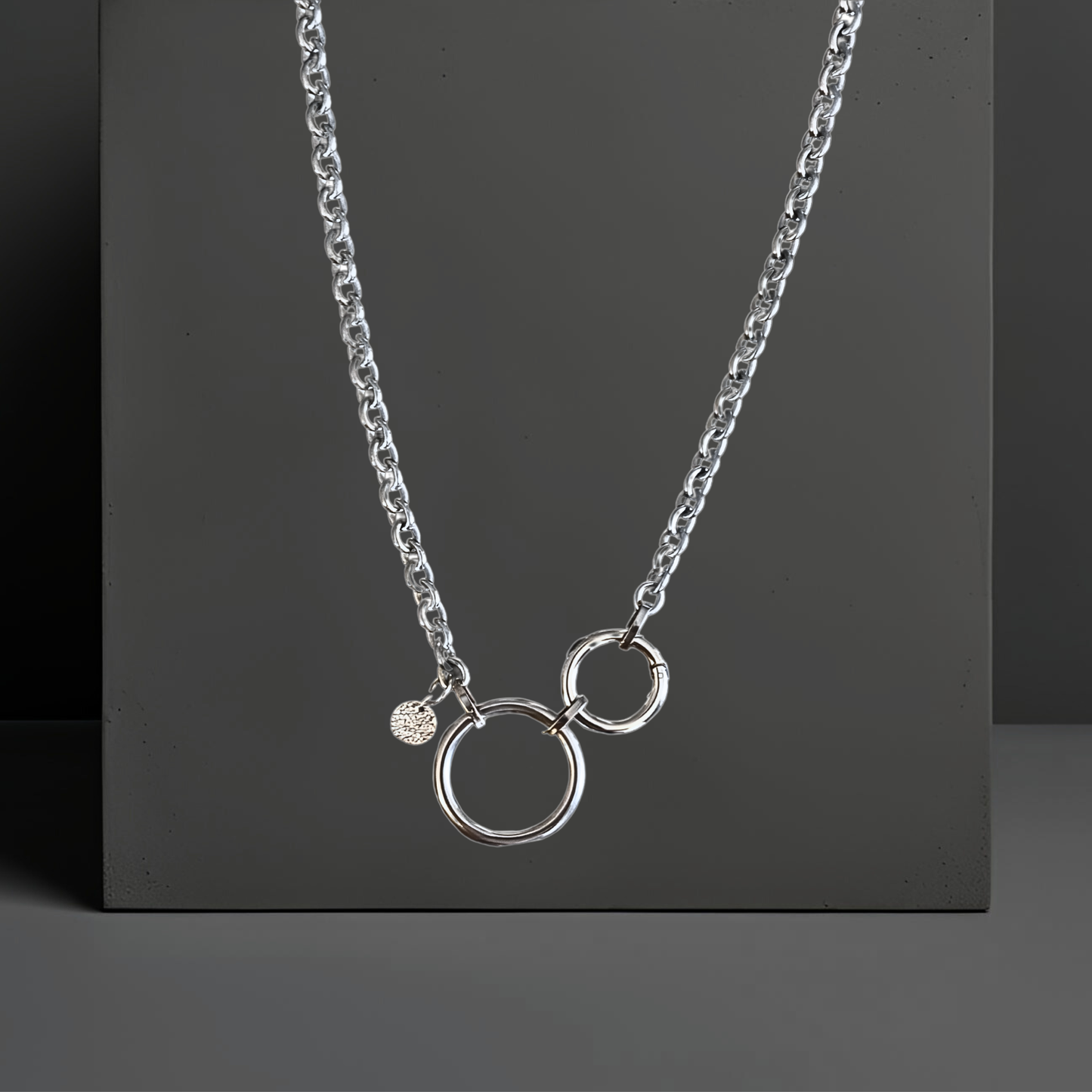 Topmodische Statement Edelstahl Halskette für Frauen. Handgefertigt von Hug the Lioness Silber und Edelstahlschmuck in Wattens, Österreich. Die Kette ist vorne mit dem Ringverschluss zu verschließen. Als Detail ist ein 10mm gehämmertes Plättchen aus Sterlingsilber angebracht. Die Kette ist 6mm breit und 65cm lang mit einem 32mm großen Ring aus Edelstahl und einem 24mm Ringverschluss.