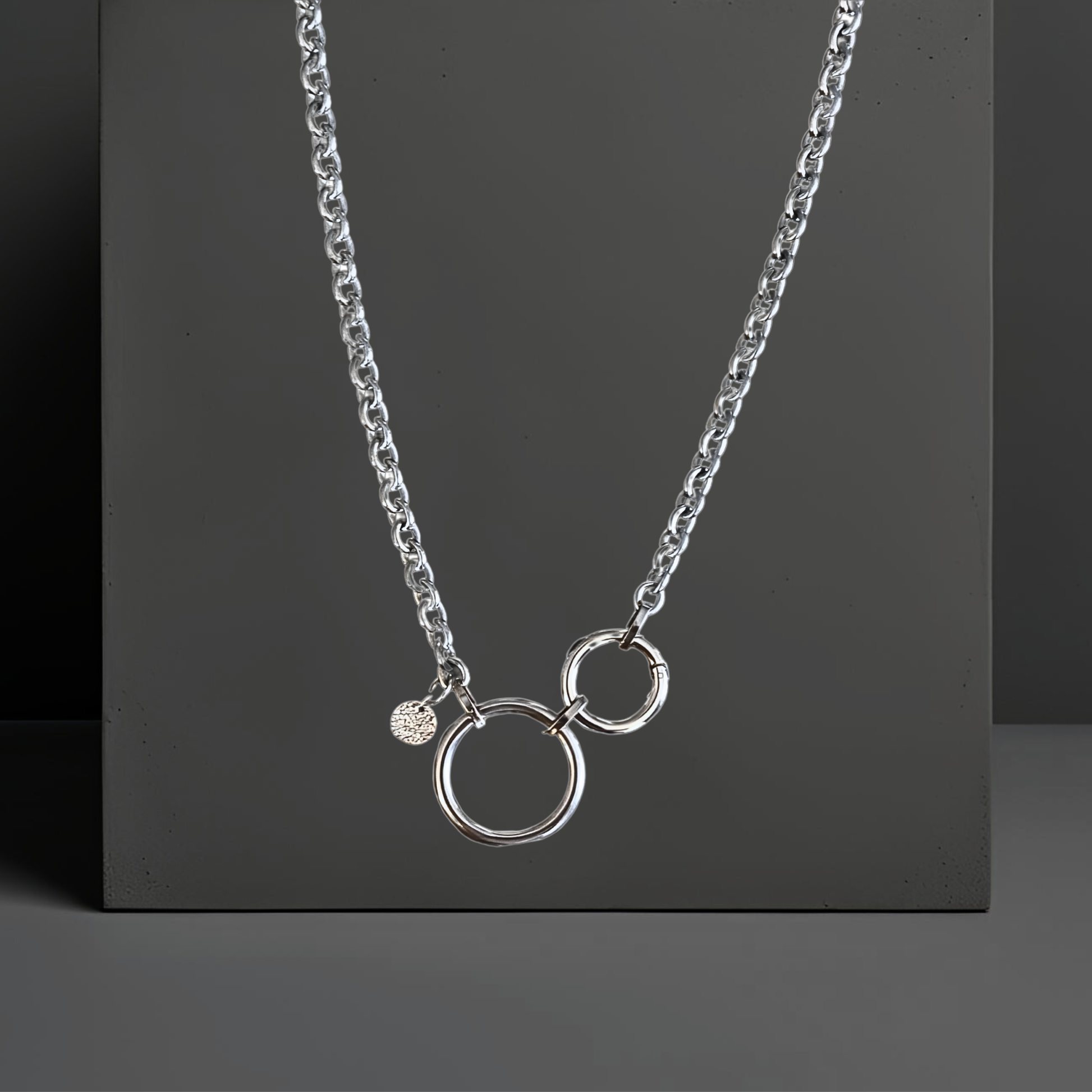 Topmodische Statement Edelstahl Halskette für Frauen. Handgefertigt von Hug the Lioness Silber und Edelstahlschmuck in Wattens, Österreich. Die Kette ist vorne mit dem Ringverschluss zu verschließen. Als Detail ist ein 10mm gehämmertes Plättchen aus Sterlingsilber angebracht. Die Kette ist 6mm breit und 65cm lang mit einem 32mm großen Ring aus Edelstahl und einem 24mm Ringverschluss.