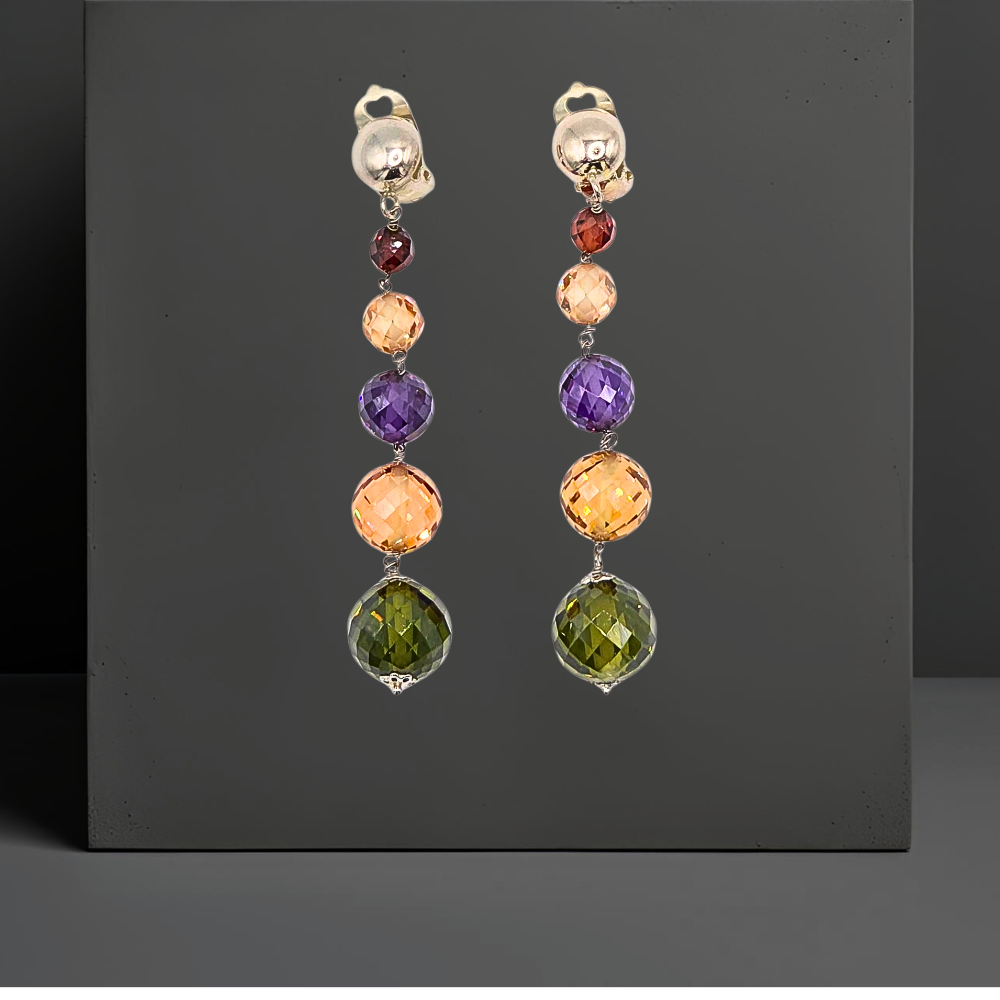 Set mit bunten Zirkonen handgefertigt:  Lederkette und Ohrclipsen mit Anhänger aus farbigen Zirkonen. Anhänger und Ohrringe sind 75mm lang und bestehen jeweils aus 5 leuchtenden, facettierten Zirkonkugeln in grün, goldgelb, violett, rose und rot    in abgestufter Größe. Der Schmuck ist von der Marke Hug the Lioness.