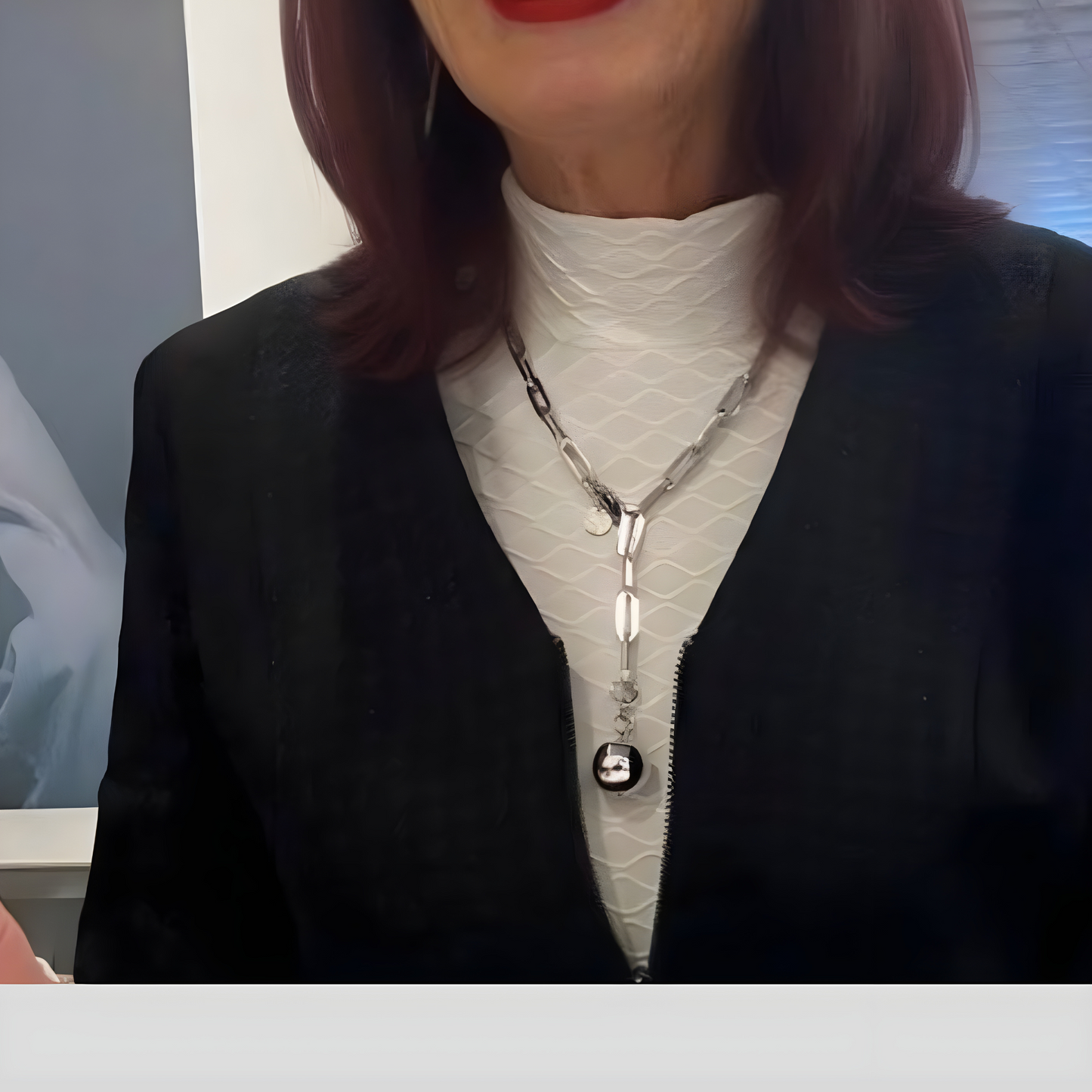 Moderne Y-Kette mit einer großen glänzenden Silberkugel als Anhänger. Die Kette ist aus silberfarbenem Edelstahl und hat 7mm breite längliche Kettenglieder. Die Halskette und ist 55cm lang. Die Kette wird getragen von einer Frau mit weißem Oberteil und schwarzem Mantel.