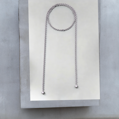 Lange Wickelkette oder Lassokette  aus silbernem Edelstahl. Die moderne Wickelkette ist 120mm lang und 6mm breit und wird einmal um den Hals geschlungen, die langen Enden hängen lose. An jedem Ende der Halskette ist eine 16mm silbergraue Mallorcaperle angebracht. Die Kette hat keinen Verschluss. Das stylishe Schmuckstück ist von der Schmuckmarke Hug the Lioness aus Österreich. 