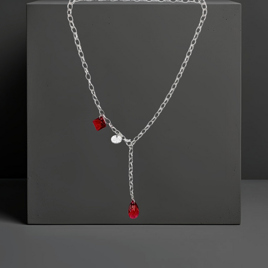 Trendige Y-Kette, Kristallkette mit 2 roten Kristallen aus 925 Sterlingsilber. Der Stil ist modern und elegant. Die Kette ist vorne zu schließen und die Länge ist variabel. Die Silberkette ist 50cm lang, am Ende ist ein roter Kristalltropfen angebracht, an der Seite ein viereckiger roter Kristall und ein gehämmertes Silberplättchen. Die Kette ist von der Schmuckmarke HUG THE LIONESS