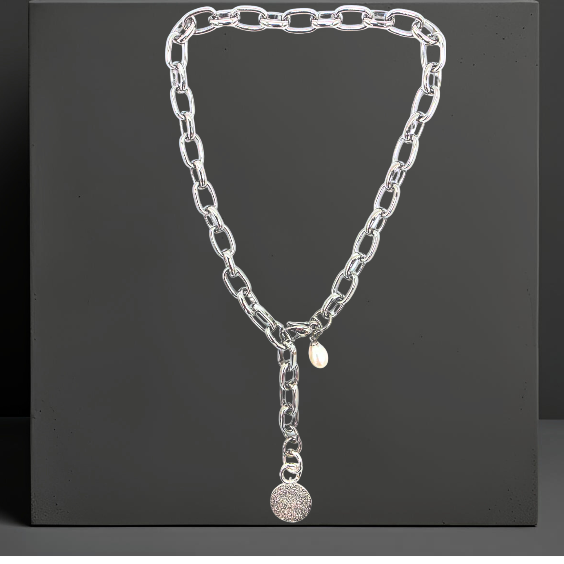 Exklusive Edelstahl Halskette für Damen von der Schmuckmarke Hug the Lioness aus Österreich.
Elegante breite Statement Y-Halskette 47cm aus 316L Edelstahl in silber. Die Halskette hat einen  Anhänger aus gehämmerten Sterlingsilber in Form einer Münze. und eine Perle. Der Karabinerverschluss ist vorne flexibel zu schließen. 